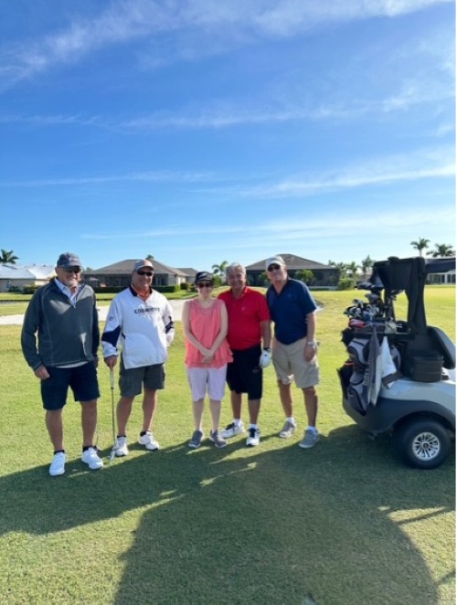 Photo of five people standing on a sunny golf course in the sun, while participating in the Special Populations Golf Classic.